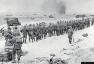 Les prisonniers sont fouillés et guidés vers la plage. Photo : US National Archives