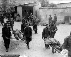 Le 31 juillet 1944, des prisonniers allemands transportent leurs morts vers le cimetière provisoire de Bréhal. Photo : US National Archives