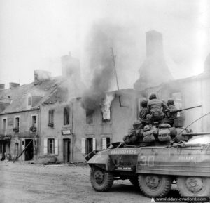 Le 26 juillet 1944, une automitrailleuse M8 Greyhound appartenant à l’escadron C du 82nd Armored Reconnaissance Battalion de la 2nd Armored Division progresse dans les rues de Canisy. Photo : US National Archives