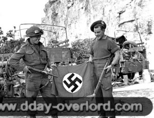 10 août 1944 : les soldats L. B. Roy et R. L. Parker du Queen’s Own Cameron Highlanders of Canada, 6th Infantry Brigade, 2nd Canadian Infantry Division, posent avec un drapeau nazi pris à l’ennemi. Photo : US National Archives