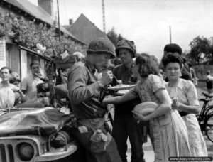 8 août 1944 : des soldats américains à côté d’une Jeep savourent un repas offert par la population de Champigné en liesse après sa libération. Il s’agirait du Captain Phillip C. Staples de la compagnie G, 2nd Infantry Regiment, 5th Infantry Division. Photo : US National Archives