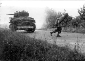 Août 1944 : un soldat américain appuyé par un char léger Stuart (équipé du système de franchissement Cullin) traverse une route sous le feu dans le secteur de Coudray. Photo : US National Archives