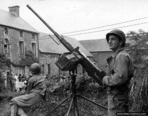 22 juillet 1944 : des soldats américains surveillent les alentours armés d’une mitrailleuse lourde M2 HB 12,7 mm (servie par le Pfc Angelo Brichellio) pendant le déroulement d’une messe devant une ferme à Couvains. Photo : US National Archives