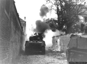 17 août 1944 : combats menés par les Canadiens du Sherbrooke Fusiliers Regiment (chars Sherman #14 et #21) de la 2nd Canadian Armoured Brigade avec les soldats Fusiliers Mont-Royal de la 2nd Canadian Infantry Division, rue des Prémontrés, contre les hommes du SS-Sturmbannführer Krause appartenant à la 12. SS Panzer-Division Hitlerjugend retranché dans l’Ecole Supérieure de Jeunes Filles. Photo US National Archives