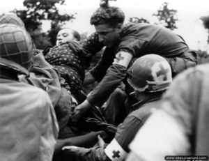 7 août 1944 : une française, qui a eu les deux jambes arrachées suite à l’explosion d’une mine antipersonnel allemande, est emmenée jusqu’au poste de secours de la 79ème division d’infanterie américaine (tenu par le 304th Medical Battalion). Photo : US National Archives