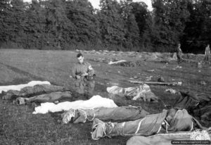 L’aumônier américain Francis L. Sampson du 501st PIR de la 101ème division aéroportée bénit les corps de parachutistes à Hiesville. Photo : US National Archives