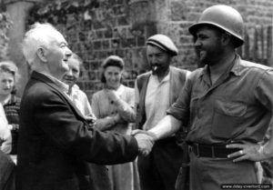 16 août 1944 à Le Grais : un soldat américain appartenant à la 9ème division d’infanterie serre la main de Paul Daniel, ingénieur à l'origine du moteur en étoile rotatif. Photo : US National Archives