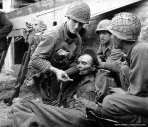 19 août 1944 : le lieutenant américain Stockridge Bacchus de la compagnie A du 314ème régiment de la 79ème division d’infanterie donne à boire à un prisonnier allemand blessé à Mantes-la-Jolie. Photo : US National Archives