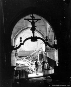Deux soldats discutent avec un prêtre au milieu des vestiges de l’église de Méautis, touchée par les bombardements. Photo : US National Archives
