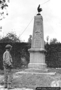 12 juin 1944 : un soldat américain observe le monument aux Morts de la Première Guerre mondiale sur la commune de Mosles. Photo : US National Archives