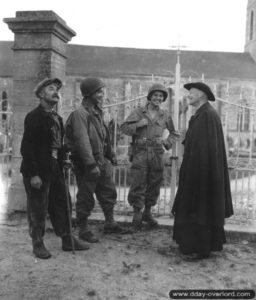 7 juillet 1944 : l’abbé Pierre Hébert et M. Gancel surnommé Chabriac en pleine discussion avec deux soldats américains devant le cimetière de Neuilly-la-Forêt. Photo : US National Archives
