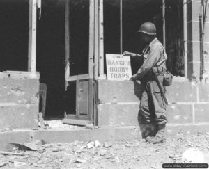 11 août 1944 : un sapeur de la B Company, 15th Engineer Combat Bn, 9th (US) Infantry Division installe un panneau signalant la présence d’un engin explosif improvisé à Perriers-en-Beauficel. Photo : US National Archives