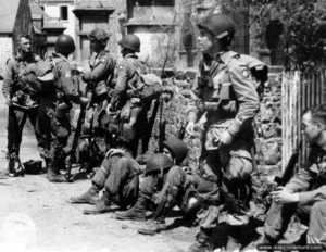 Un stick commandé par le capitaine Kenneth Johnson de la HQ Company du 508th Parachute Infantry Regiment, 82nd Airborne Division, loin de sa zone de saut initialement prévue, progresse vers le sud le Jour J et marque une courte pause dans Ravenoville le 6 juin 1944. Photo : US National Archives