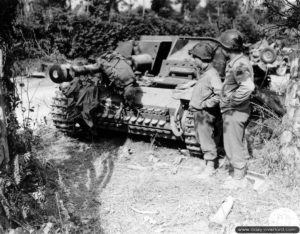 1er août 1944 : des soldats américains de la 3rd (US) Armored Division observent un Stug III abandonné par les Allemands dans le secteur de Roncey. Le cadavre d'un soldat allemand se trouve sur le canon du blindé. Photo : US National Archives