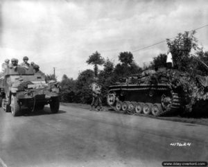 13 août 1944 : des soldats américains observent depuis leur semi-chenillé M3A1 l’épave d’un Sturmgeschütz III abandonné par les Allemands sur une route de Saint-Germain-de-Tallevende. Photo : US National Archives