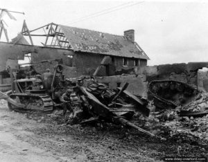 27 juillet 1944 : les vestiges de deux chars allemands Panzer IV appartenant aux 5ème et 8ème compagnie du 130. Panzerlehr-Regiment tractés par un bulldozer américain dans le secteur de Saint-Gilles. Photo : US National Archives