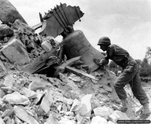 Un soldat de la police militaire de la 2ème division d’infanterie américaine, James Sundschuh, inspecte la cloche de l'église en ruines de Saint-Jean-des-Baisants. Photo : US National Archives