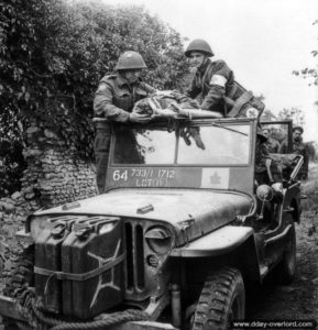 3 juillet 1944 : le Major John W. Forth, aumônier du Cameron Highlanders of Ottawa et un infirmier installent un blessé sur civière à bord d’une Jeep dans le secteur de Saint-Manvieu-Norrey. Photo : Archives nationales canadiennes