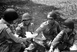 5 juin 1944 : des parachutistes américains appartenant au 2ème bataillon du 508th PIR, 82nd Airborne Division, lisent le message d’encouragement du général Eisenhower avant l’embarquement sur l’aérodrome RAF Saltby. Photo : US National Archives