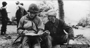 7 juin 1944 : un lieutenant appartenant aux Civil Affairs du 5ème corps américain s’entretient avec Gustave Joret, ouvrier agricole, au sujet des dernières positions allemandes connues. Ce dernier est blessé quelques heures après la prise de cette photo par le tir d’un soldat américain et meurt des suites de sa blessure le 12 juin 1944. Photo : US National Archives