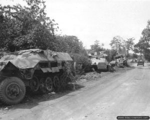 31 juillet 1944 : une Jeep longe un convoi de véhicules allemands et un char Sherman détruits sur la route départementale 49 au lieu dit de La-Lande-des-Morts sur la commune de Trelly.