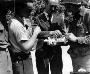 6 août 1944 : Marc Didier, habitant de Tribehou présente à des soldats américains un dispositif ingénieux de récepteur radio dissimulé dans une boîte de cigares. Photo : US National Archives