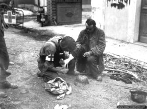 19 août 1944 : un infirmier canadien soigne la jambe d’un prisonnier allemand à Trun. Photo : US National Archives