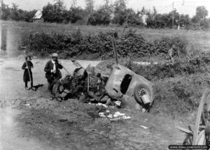 10 août 1944 : un père et sa fille habitant le secteur de Vengeons observent l’épave d’une Simca 8 détruite avec un soldat allemand tué à son bord. Photo : US National Archives