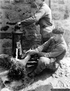 2 août 1944 : le soldat C. L. Scott de la 4ème division d’infanterie américaine profite de la fontaine publique de Villedieu-les-Poëles pour entreprendre un brin de toilette. Photo : US National Archives