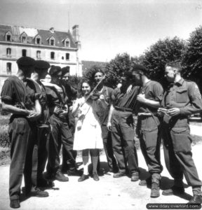 5 juillet 1944 : Charlotte Coustenoble, âgée de 13 ans et ayant fuit sa ville de Rots, joue du violon pour des soldats canadiens à Villiers-le-Sec. Photo : US National Archives