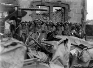 29 juillet 1944 : des éléments de l’arrière garde allemande faits prisonniers par des soldats de la 4ème division d’infanterie américaine à Coutances. Photo : US National Archives
