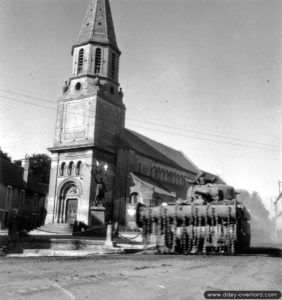15 juin 1944 : un char Sherman Crab appartenant au 2nd County of London Yeomanry (Westminster Dragoons), 30th Armoured Brigade, progresse devant l’église Saint Martin. Photo : US National Archives