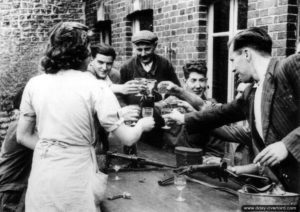 Moment de détente pour ces civils et résistants français qui trinquent à la libération d'Écouché. Photo : US National Archives