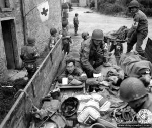 Des blessés américains appartenant à la 82nd Airborne Division sont évacués à bord d'un camion depuis un poste médical improvisé dans une maison d'Étienville. Photo : US National Archives