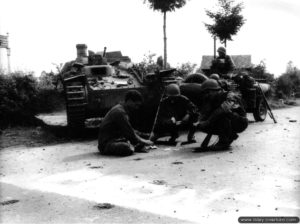 Des soldats américains de la 9th (US) Infantry Division jouent aux cartes devant l’épave d’un SdKfz 140 (ayant appartenu à la 116. Panzer-Division) sur un carrefour du secteur de Ferté-Macé. Photo : US National Archives