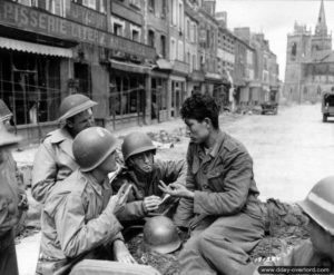 11 juillet 1944 : le première classe Francis Leu et le correspondants John Prince du London Times et Philip Grune, du London Evening Standard interrogent un prisonnier asiatique sous l’uniforme allemand à La-Haye-du-Puits. Photo : US National Archives