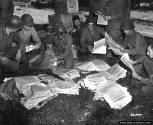 9 août 1944 : distribution du journal Stars & Stripes pour ces soldats appartenant à la 28ème division d’infanterie américaine à Saint-Manvieu-Bocage. Photo : US National Archives