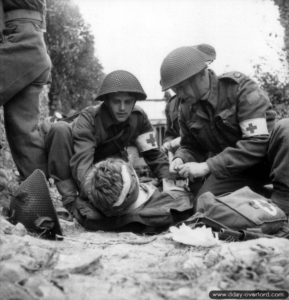 15 juillet 1944 : des infirmiers appartenant au Cameron Highlanders of Ottawa (Machine Gun) de la 3e division d’infanterie canadienne prennent en charge un soldat blessé dans le secteur de Saint-Manvieu-Norrey. Photo : Canada National Archives