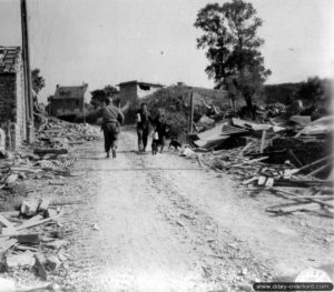 Des habitants de Tourlaville rentrent de la corvée d’eau au milieu des ruines la commune. Photo : US National Archives
