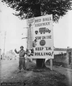 5 septembre 1944 : le caporal Chales H. Johson du 783rd Military Police Battalion pose devant un panneau symbolisant le succès de la Red Ball Express, rue de Bretagne à Alençon. Photo : US National Archives
