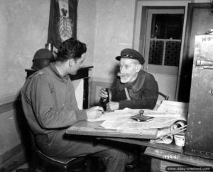 11 juillet 1944 : le capitaine Jean-Jacques La Rûs, 8th Infantry Division, des Civils Affairs de la prend en charge un civil normand, monsieur Eugène Sérée, qui doit être relogé à La-Haye-du-Puits. Photo : US National Archives