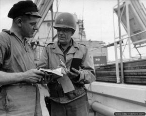 Discussion entre le Major E.D. Hill et Jack Williams concernant le déchargement du tanker visible sur la photo à Port-en-Bessin pour ravitailler les troupes alliées en carburant. Photo : US National Archives