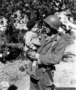 23 juin 1944 : le soldat de première classe Jesse De Vore avec un jeune enfant de Trévières. Photo : US National Archives