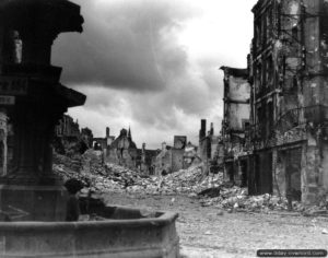 17 août 1944 : un soldat appartenant au Cameron Highlanders de la 3ème division d’infanterie canadienne observe les ruines depuis sa position dans la fontaine à la recherche d’un éventuel tireur isolé allemand. Photo US National Archives