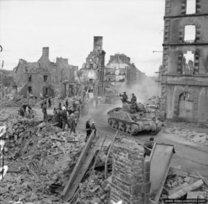 17 août 1944 : un char Sherman progresse dans les ruines de Flers devant les habitants normands. Photo : IWM