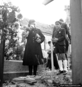 14 juillet 1944 : Louise Godin et son fils Jean-Claude devant la tombe de Léon Peronne à Rots. Photo : US National Archives
