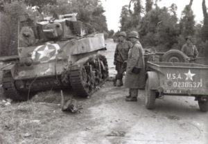 Des Américains inspectent l’épave d’un char M3 Stuart détruit par un tir de Panzerfaust le 7 juin 1944 sur le carrefour au sud de Saint-Côme-du-Mont, le « Dead Man’s Corner ». Photo : US National Archives