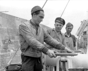 Ouverture d’une vanne du pipeline de Port-en-Bessin pour les deux militaires américains et le militaire britannique (au centre), dans le cadre de l'opération PLUTO permettant le ravitaillement des armées en carburant ("minor system"). Photo : US National Archives