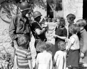 23 juin 1944 : le soldat Leonard Dodson et le première classe James Girardi fraternisent avec des habitants de Trévières. Photo : US National Archives