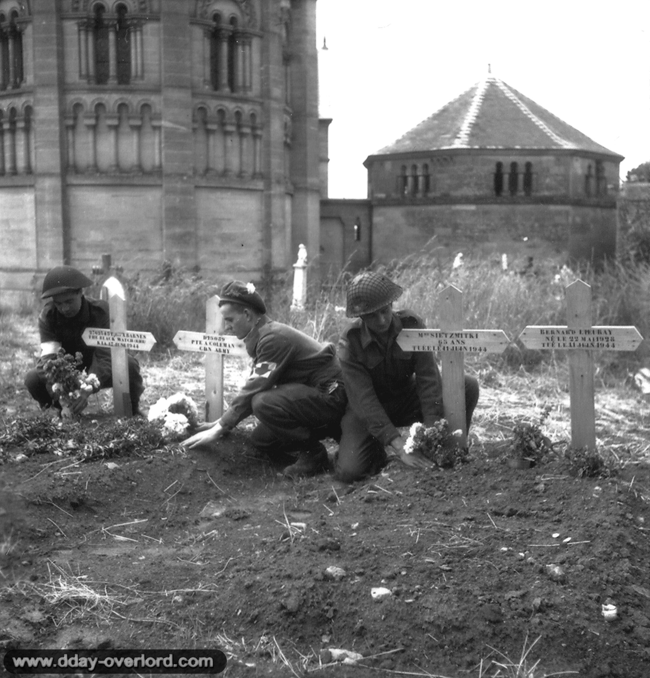 W. Young, H. Roach et M. G. Newberry de la 23rd Field Ambulance de la 3e division d’infanterie canadienne fleurissent des tombes au pied de l’église de Basly. Photo : US National Archives
